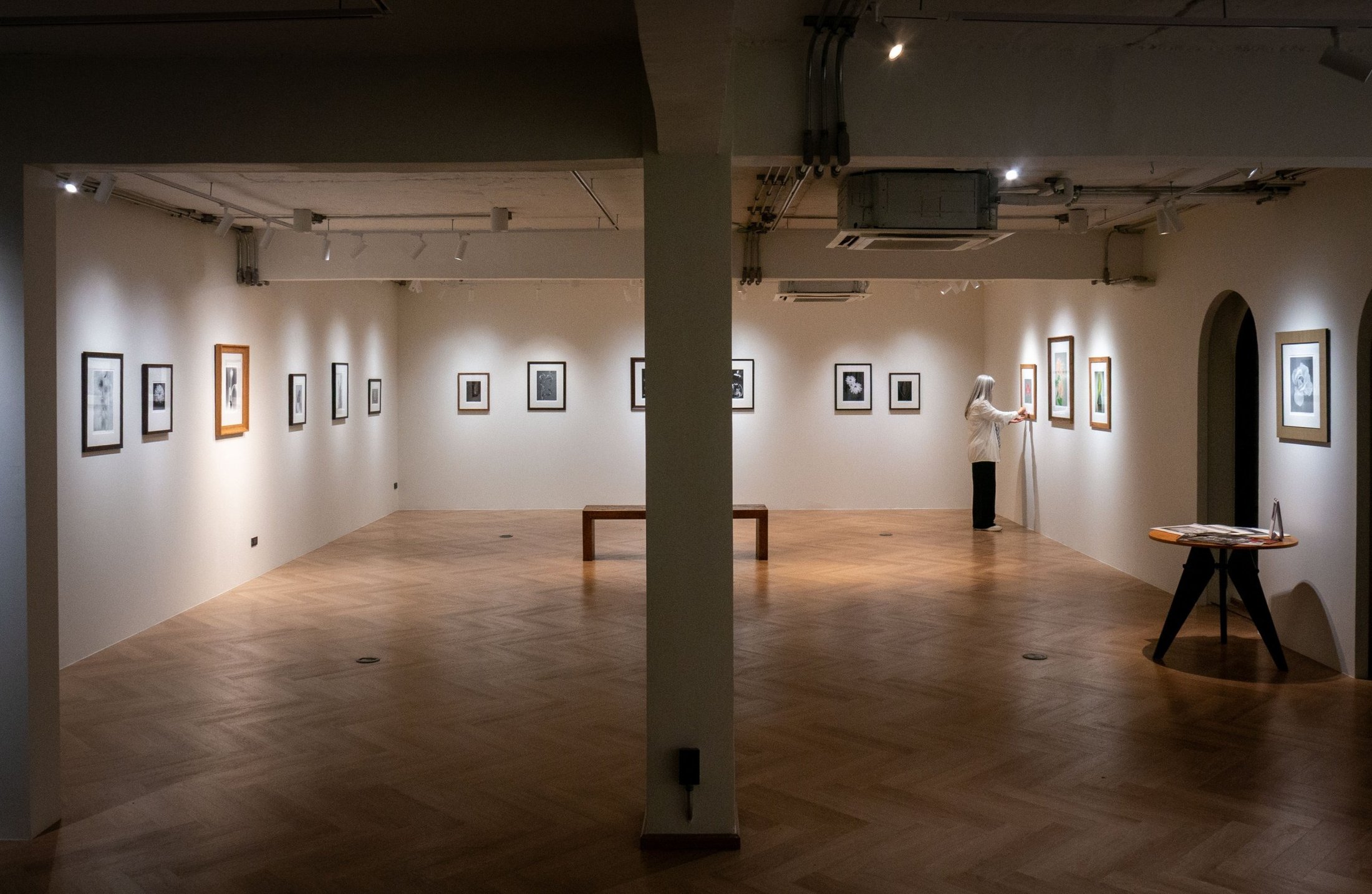 Installation view of The Exquisite Silence: framed photographs hung on white walls above a herringbone floor